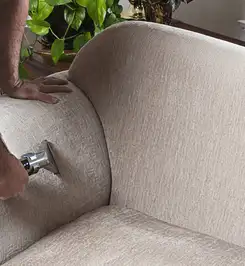 Professional upholstery cleaner deep-cleaning a fabric sofa with a handheld extraction tool and hose Tuscaloosa, AL.